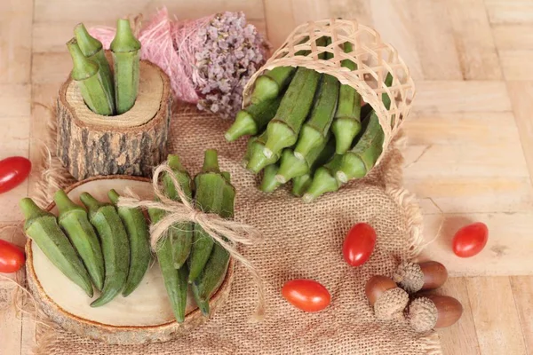 Vainas de okra frescas y rebanadas sobre fondo de madera — Foto de Stock