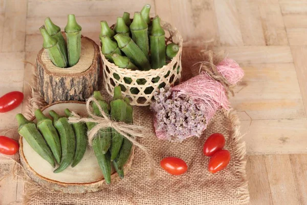 Vainas de okra frescas y rebanadas sobre fondo de madera — Foto de Stock