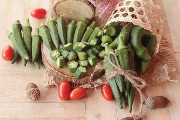 Verse okra peulen en gesneden op houten achtergrond — Stockfoto