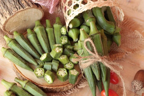 Färsk okra baljor och skivad på trä bakgrund — Stockfoto