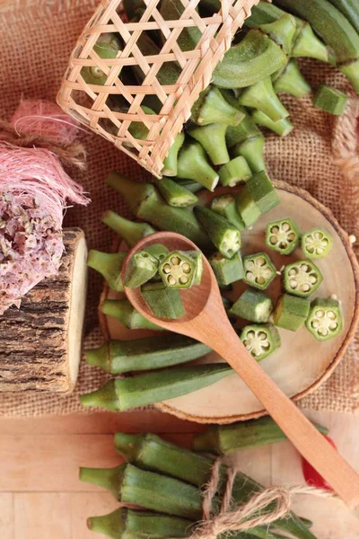 Vainas de okra frescas y rebanadas sobre fondo de madera — Foto de Stock