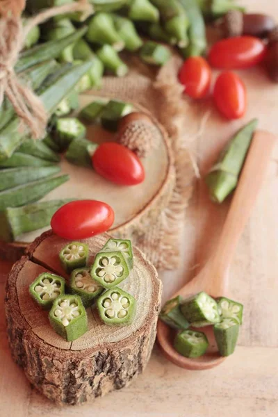 Vainas de okra frescas y rebanadas sobre fondo de madera — Foto de Stock