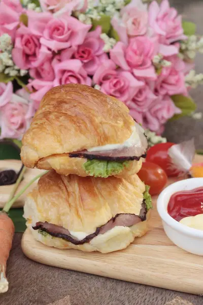 Croissant-Sandwich mit gegrilltem Schweinefleisch, Gemüse und Käse. — Stockfoto