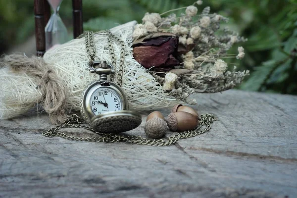Antique pocket watch and hourglass with dried flowers.