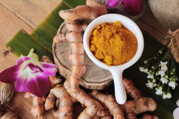 Rădăcină de turmeric cu pulbere de turmeric pe fundal de lemn — Fotografie, imagine de stoc