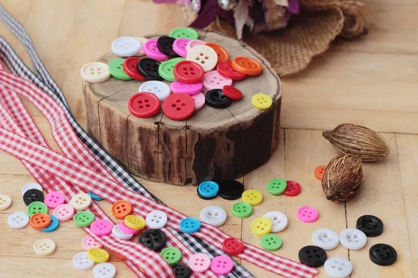 Kolorowe przyciski z tworzyw sztucznych do szycia na tle drewna — Zdjęcie stockowe