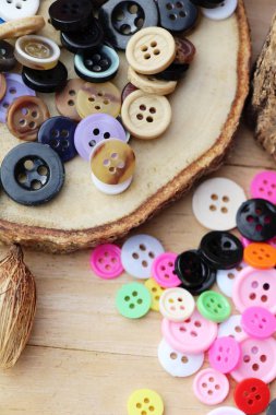 Dikiş ahşap arka plan üzerinde renkli plastik düğmeler