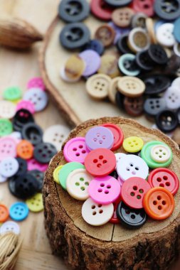 Dikiş ahşap arka plan üzerinde renkli plastik düğmeler