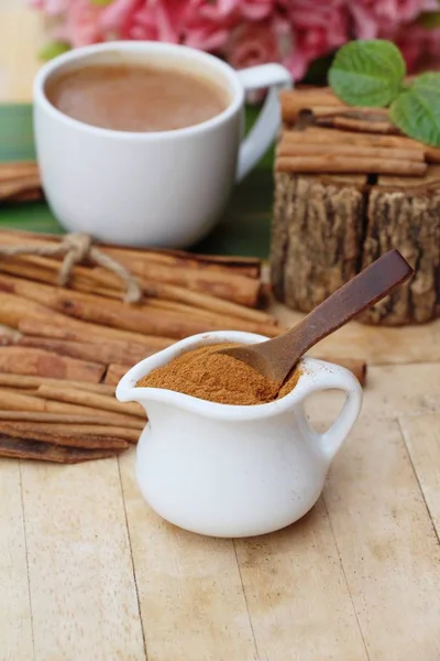 Coffee cup with cinnamon powder and sticks