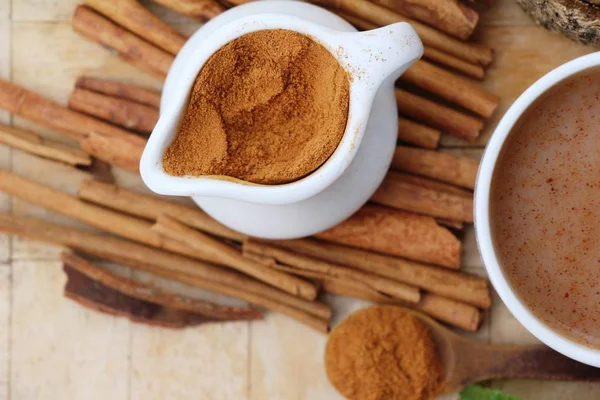 Coffee cup with cinnamon powder and sticks