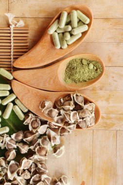 Ahşap arka plan üzerinde sağlık için Moringa kapsül