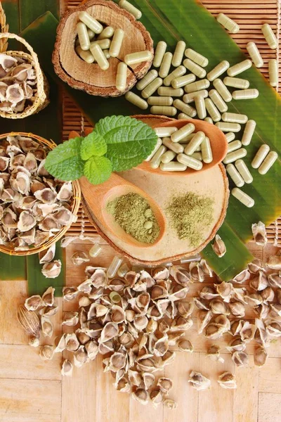 Ahşap arka plan üzerinde sağlık için Moringa kapsül