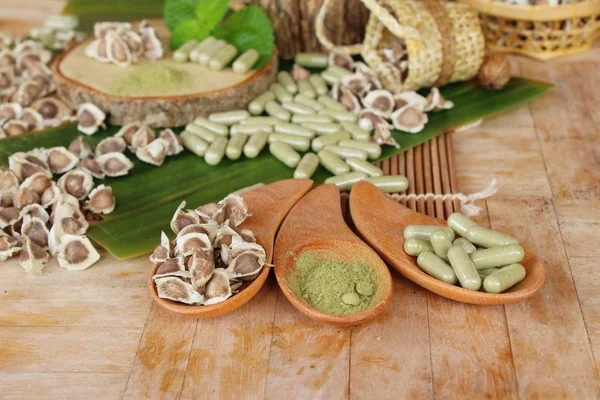 Ahşap arka plan üzerinde sağlık için Moringa kapsül