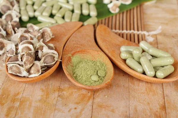 Ahşap arka plan üzerinde sağlık için Moringa kapsül