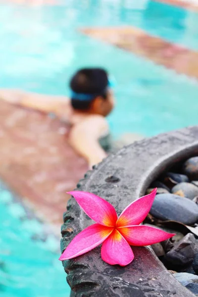 Garçon nage dans la piscine avec des fleurs — Photo