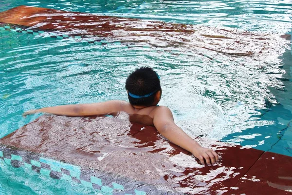 Chlapec je plavání v bazénu s květinou — Stock fotografie