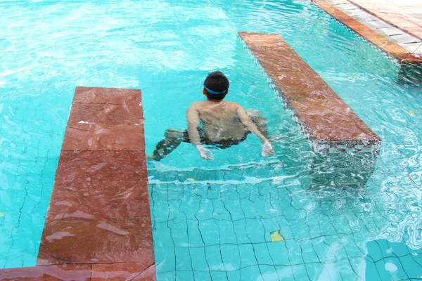 Chlapec je plavání v bazénu s květinou — Stock fotografie