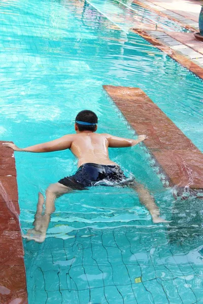 Boy is swimming in pool with flower — Stock Photo, Image