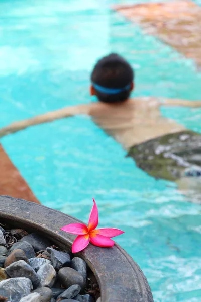 Boy is swimming in pool with flower — Stock Photo, Image