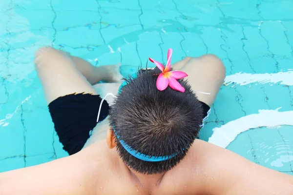 Garçon nage dans la piscine avec des fleurs — Photo