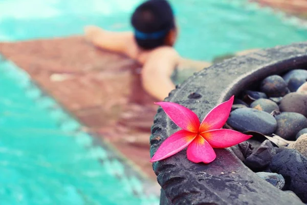 Ragazzo sta nuotando in piscina con fiore — Foto Stock