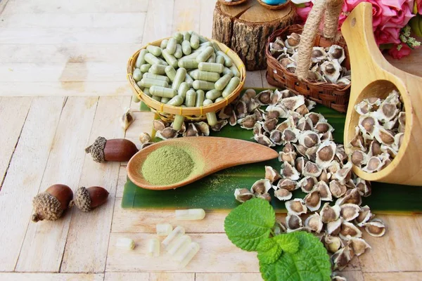 Ahşap arka plan üzerinde sağlık için Moringa kapsül