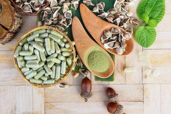 Ahşap arka plan üzerinde sağlık için Moringa kapsül