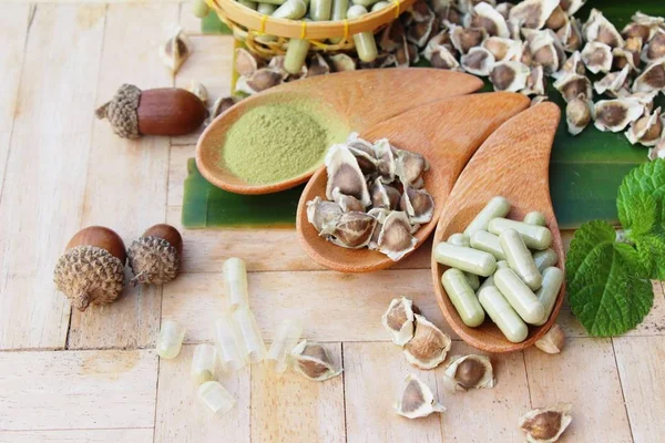 Ahşap arka plan üzerinde sağlık için Moringa kapsül