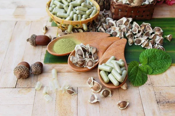 Ahşap arka plan üzerinde sağlık için Moringa kapsül