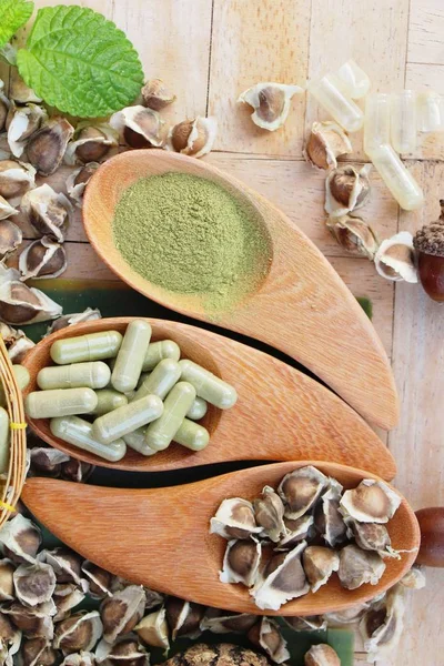 Ahşap arka plan üzerinde sağlık için Moringa kapsül