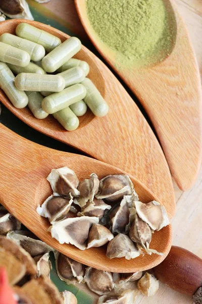 Ahşap arka plan üzerinde sağlık için Moringa kapsül