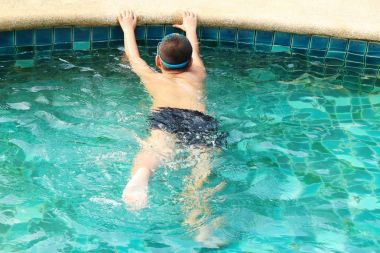 Çocuk havuzda yüzüyor.