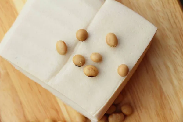 Tofu e sementes de soja sobre fundo de madeira — Fotografia de Stock