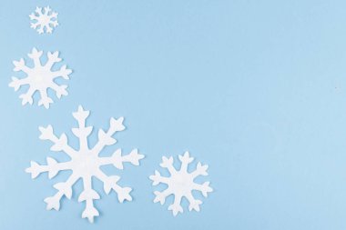 Noel ya da yeni yıl kompozisyonu mavi arka planda hissedilen kar tanelerinden yapılır. Dekoratif oyuncaklarla kış sezonu arkaplanı, asgari konsept. Düz yatıyordu. Boşluğu Kopyala