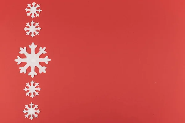 Kırmızı arka planda hissedilen kar tanelerinden yapılmış Noel ya da yeni yıl kompozisyonu. Dekoratif oyuncaklarla kış sezonu arkaplanı, asgari konsept. Düz yatıyordu. Boşluğu Kopyala