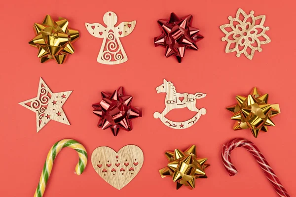 Holiday decorations. Composition made of red and gold bows, wooden Christmas tree toys, candy canes on red background. top view, closeup — Stock Photo, Image