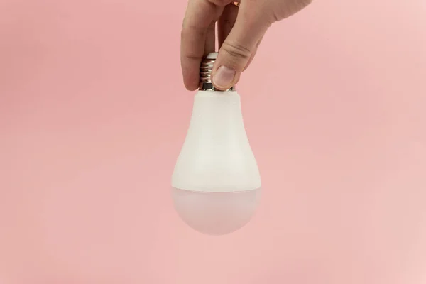 Lâmpada LED de poupança de energia nas mulheres mão em rosa bacground close up. Conceito de poupança de energia — Fotografia de Stock