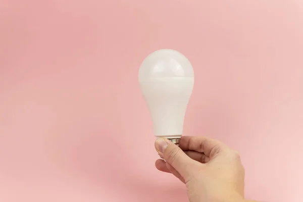 Lâmpada LED de poupança de energia nas mulheres mão em rosa bacground close up. Conceito de poupança de energia — Fotografia de Stock