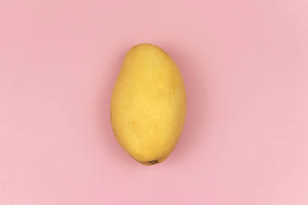 Pembe arka planda taze sarı mango meyvesi. Minimalizm. Üst Manzara. Metin için boşluk