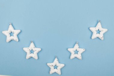 Tatil süslemeleri. Beyaz yıldızlardan oluşan yaratıcı bir kompozisyon. Açık mavi arka planda Noel ağacı oyuncakları. Üst manzara, yakın çekim. Boşluğu kopyala
