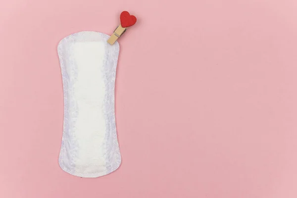 Vit daglig, menstruationskvinna pad för hygien eller blodperiod med röd nål med ett hjärta som symbol för kropp kärlek. Begreppet kvinnliga intima hygienprodukter. Kopiera utrymme, rosa bakgrund — Stockfoto
