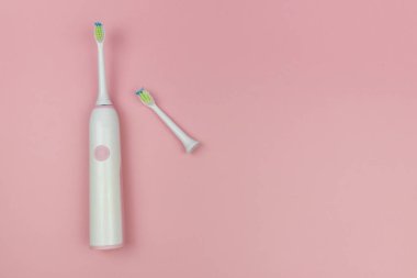 Elektrikli diş fırçası, yeni bir kafa ve yumuşak açık pembe arka planda kullanılmış bir tane. Ağız boşluğu ev sağlığı teknolojisi, tıbbi konsept. Boşluğu kopyala, üst görünüm