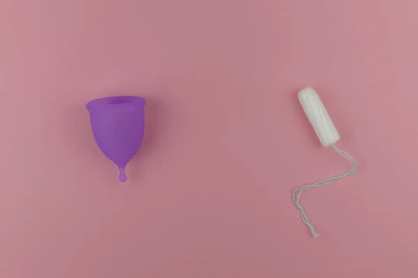 Pembe regl kupası ve menekşe renginde tampoo. O dönemde alternatif kadın hijyen ürünü. Regl, koruma, karşılaştırma konsepti, düz konum, üst görünüm