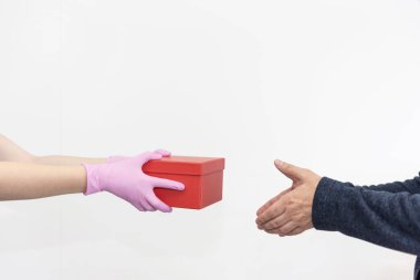 Koruyucu pembe eldivenli kurye bir kutuyu bir müşteriye teslim ediyor. Karantinaya alın. Coronavirus veya Cvid-19. Virüs koruma konsepti. İnternetten alışveriş ve ekspres teslimat. Beyaz zemin. Boşluğu Kopyala