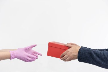 Koruyucu pembe eldivenli kurye bir kutuyu bir müşteriye teslim ediyor. Karantinaya alın. Coronavirus veya Cvid-19. Virüs koruma konsepti. İnternetten alışveriş ve ekspres teslimat. Beyaz zemin. Boşluğu Kopyala