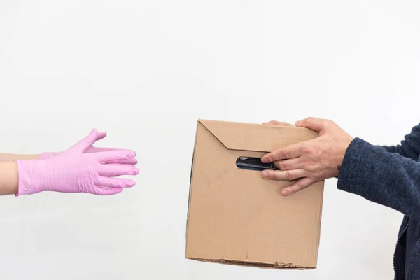 El mensajero con guantes protectores de color rosa entrega una caja de comida a un cliente. Cuarentena. Distanciamiento social. Concepto de protección antivirus. Compras en línea y entrega urgente. Fondo blanco. Copiar espacio —  Fotos de Stock