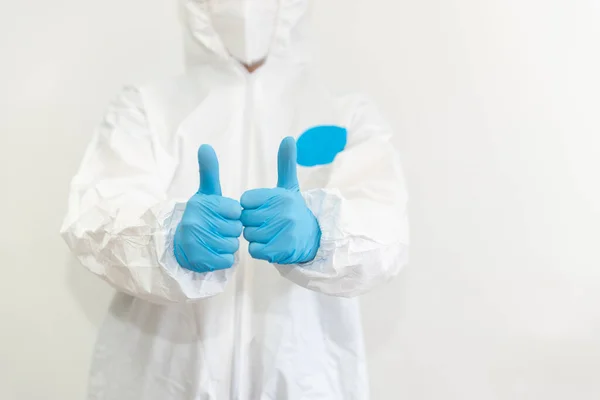 Beyaz koruyucu giysili, tıbbi maskeli ve mavi eldivenli doktor onayladı. Salgın, Coronavirus covid 19 salgını. Yüzü olmadan. Boşluğu Kopyala