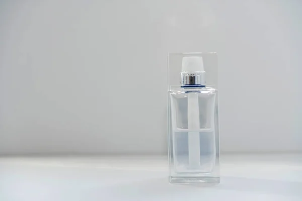 Half-full transparent perfume spray flacon on white background. Selective focus. Copy Space. — Stock Photo, Image