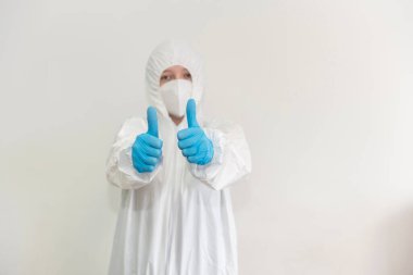 Beyaz koruyucu giysili, tıbbi maskeli ve mavi eldivenli doktor onayladı. Salgın, Coronavirus covid 19 salgını. Boşluğu Kopyala