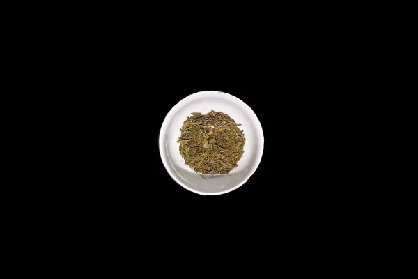 Imagen de stock de té verde seco en un tazón aislado fondo negro —  Fotos de Stock